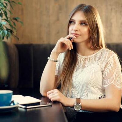 A young business woman at a coffee shop thinking about a clever pick up line